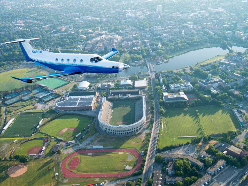 pc-12 flies over a college football stadium